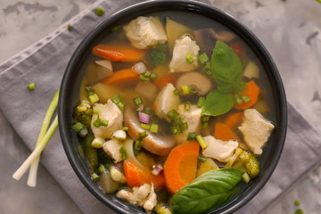 Black bowl with delicious turkey soup on napkin, close up