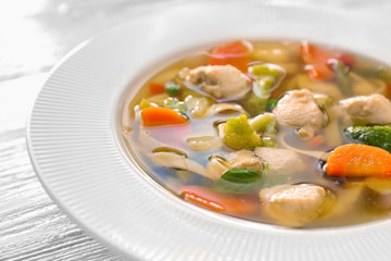 Plate with delicious turkey soup on wooden background, close up
