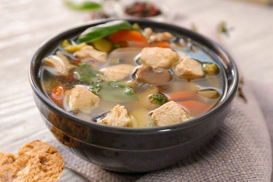Black bowl with delicious turkey soup on wooden background, close up