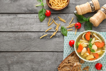 Bowl with delicious turkey soup on wooden background