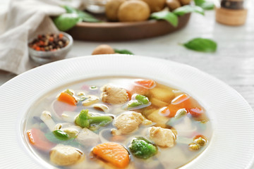 Plate with delicious turkey soup on table