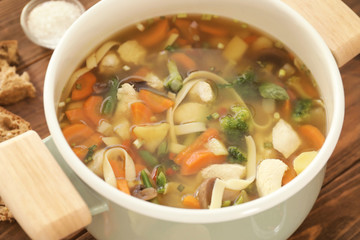 Saucepan with delicious turkey soup on table