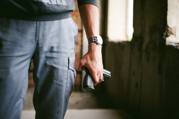 Dangerous athletic man, holds a gun in his hands, close-up. Wristband and watch