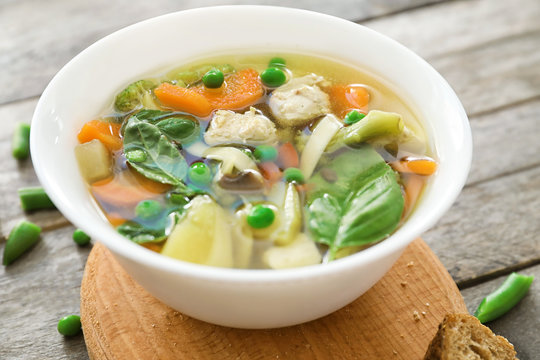 Bowl with delicious turkey soup on wooden board
