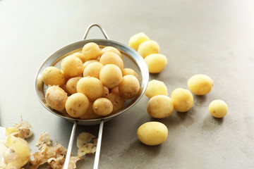 Strainer with raw organic potatoes on table