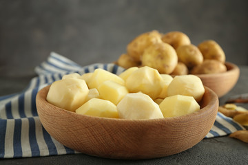 Bowl of raw peeled potatoes on table