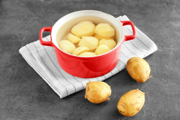 Cooking pot with raw organic potatoes on table