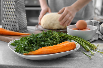 Ingredients for baking carrot cake and woman kneading dough in kitchen