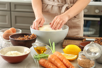 Woman kneading dough for carrot cake in kitchen