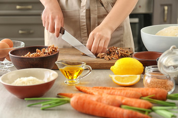 Woman cutting walnut on wooden board for carrot cake