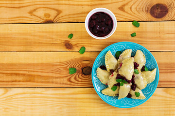 Delicious dumplings with cherry on wooden background