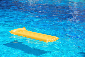 Inflatable yellow mattress in blue swimming pool
