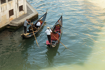 Tourists float in gondola on canal in Venice
