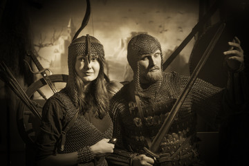 Bearded man and girl in medieval knight costumes with chain mail and swords and bows