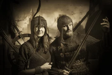 Foto op Plexiglas Bearded man and girl in medieval knight costumes with chain mail and swords and bows © dvoinik
