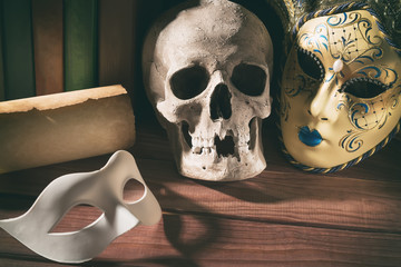 Theater and drama concept. Human skull, venetian masks with old scroll and books on wooden table © Nikolay N. Antonov