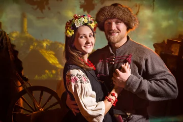 Foto op Plexiglas bearded man in a medieval Cossack costume and a girl in a Ukrainian national costume and a wreath on her head. Couple hugging © dvoinik
