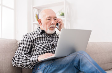 Senior man talking on phone with laptop