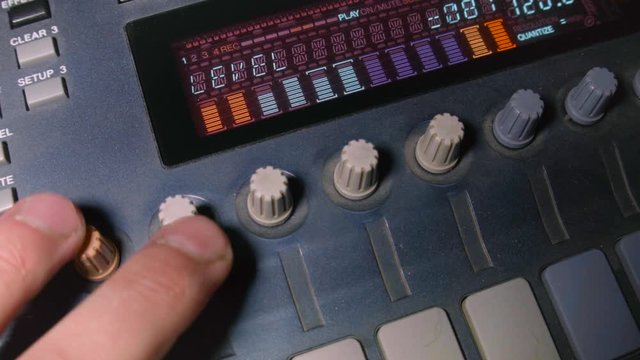 Closeup of a DJ hand tweaking knobs on the electronic musical device
