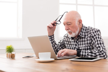 Worried senior man using laptop at home