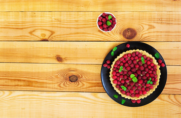 Delicious tart with custard and raspberry on wooden background