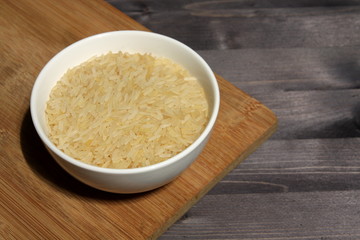 Long grain rice in a white plate on a wooden table