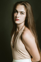 Art portrait of a beautiful girl with long hair on a dark background in the studio