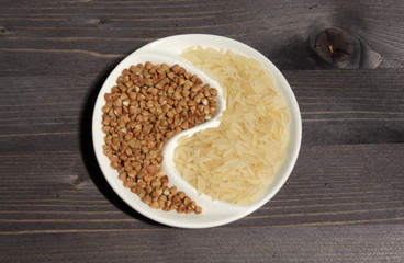 Rice and buckwheat in a plate in the shape of a yin yang sign on a table
