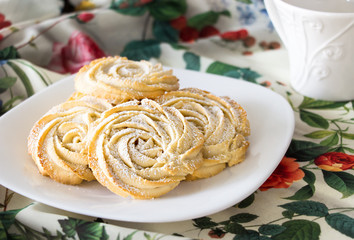 Round shortbread cookies in the form of roses. On a white plate