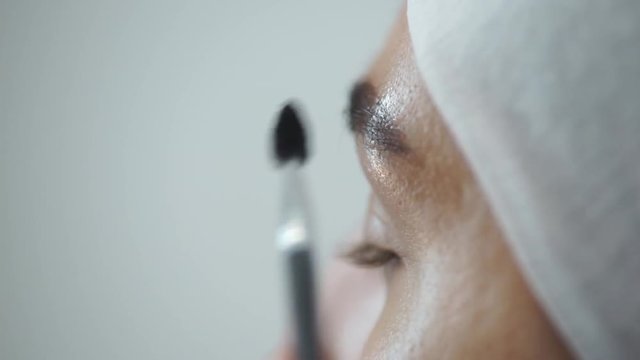 Professional make-up artist drawing eyebrows of client with henna Make-up artist combs the client's eyebrows with a brush