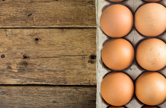 chicken eggs in brown pulp mold  tray package on wooden table , top view, with copy space