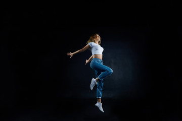 Studio shot of beautiful young European woman dancer with slim flexible body practising indoors, sharpening her dancing skills, dressed in sensible clothing. People, hobby and active lifestyle concept