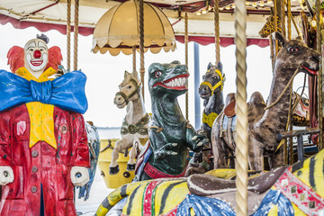 Vieux manège bizarre,  carrousel avec clown terrifiant, dinosaure menaçant