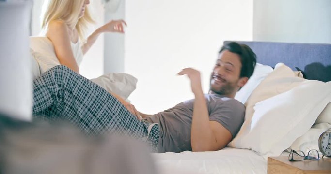 Blonde woman and man joking and pillow fighting. Couple in love morning wake up at home in bedroom. Caucasian girlfriend and boyfriend people liying on bed. Lovely strokes. 4k video