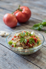 Bowl of fresh organic quinoa salad on wooden table. Shallow depth of field.
