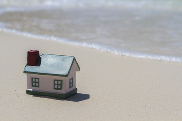 Toy houses on the sand near the water.
