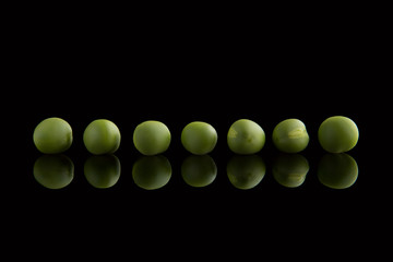 Young green peas on a black background
