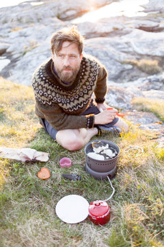 A man cooks cod on a camp fire on the Lofoten islands, Norway