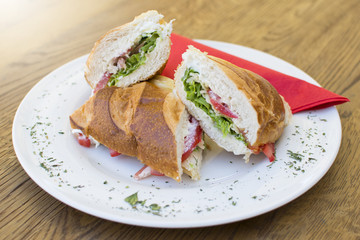 Delicious sandwiches with ham, tomato, cheese, and lettuce. Beautiful and tasty meal at the restaurant on a sunny day.
