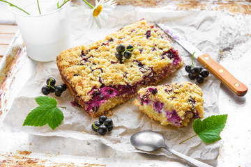 Black currant and cottage crumble cake on baking paper and rustic background