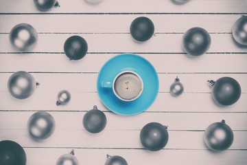 Coffee cup and christmas balls on white background.