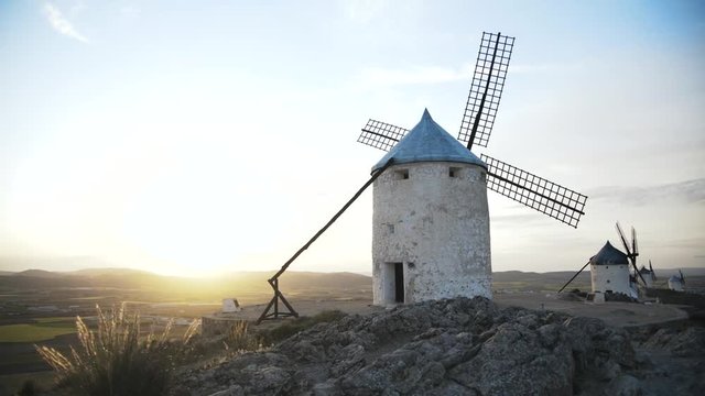Panoramic view of Consuegra, Toledo province, Castilla la Mancha, Spain. Old windmills and a castle in the background. Grass in the wind. Locked down real time medium shot