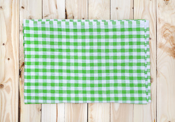 Green checkered tablecloth on wooden table, top view