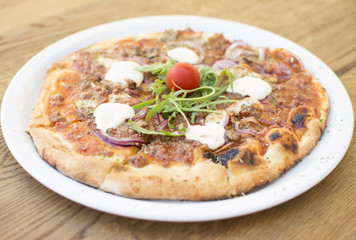 Hot pizza with melting cheese on a rustic wooden table. Delicious meal in the restaurant on a sunny day.