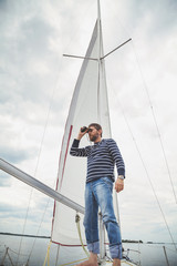 Fototapeta premium captain in striped shirt looking through binoculars sailing yacht
