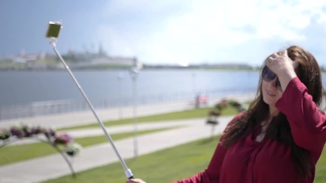 Beautiful young girl doing photo on selfie stick against the background of the bay and beautiful scenery. HD, 1920x1080. Slow motion