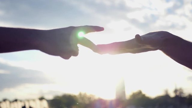 Men play the game on their hands, stone, paper scissors, against the sunset background with the effect of the lens. HD, 1920x1080. Slow motion
