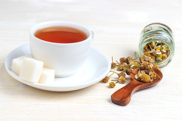 Tea in a cup with a sugar cube and a wooden spoon