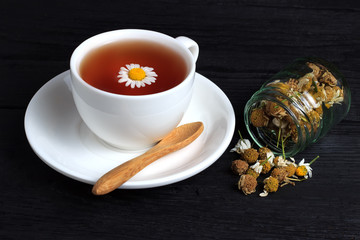 Cup of tea with chamomile in a white cup on a black background