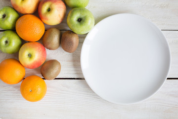 Ripe apples, orange and kiwi on a wooden background